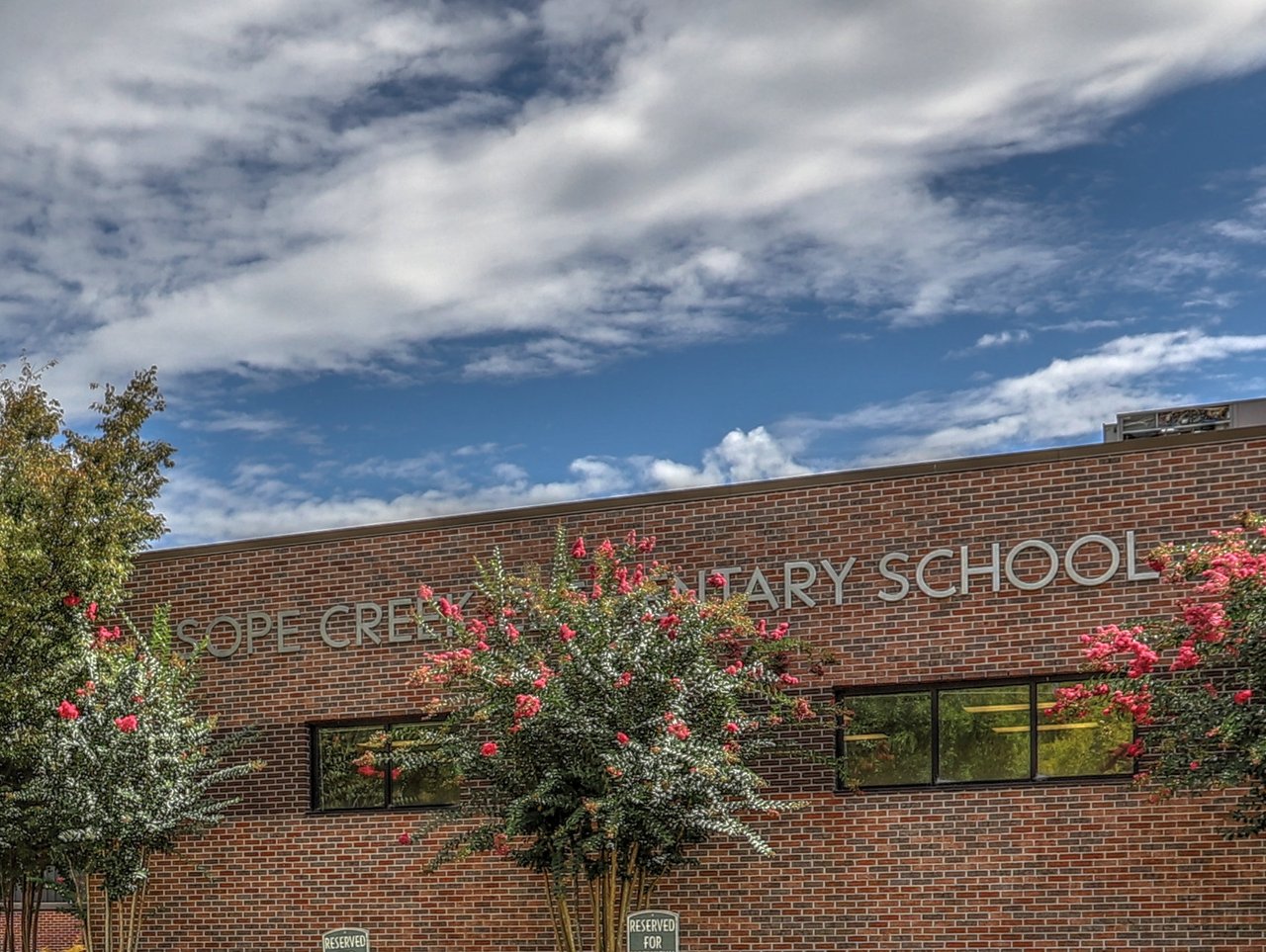 Sope Creek Elementary School’s brick facade, partly screened by flowering trees.