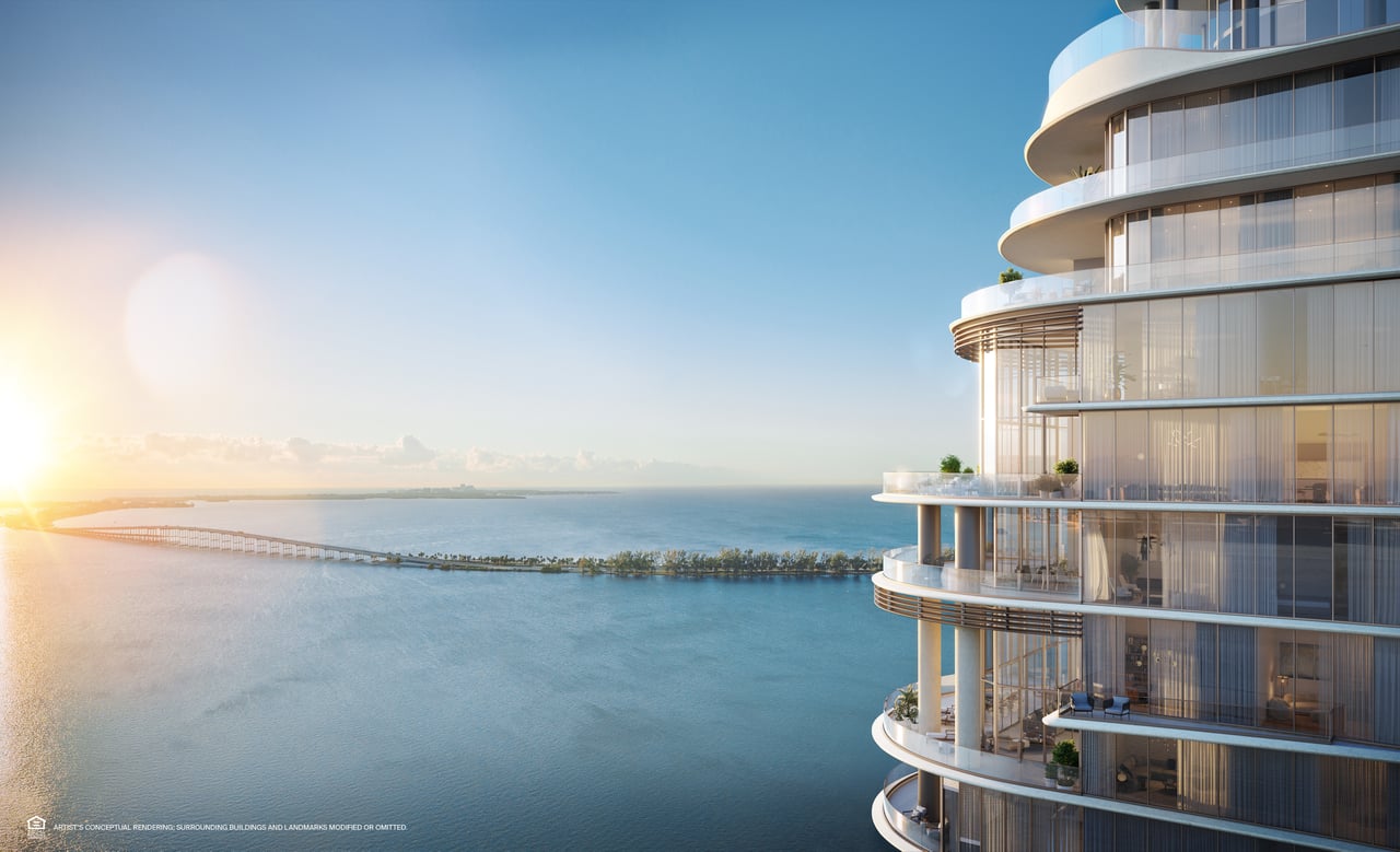 Waterfront high-rise with curved balconies overlooking the bay and a distant bridge.