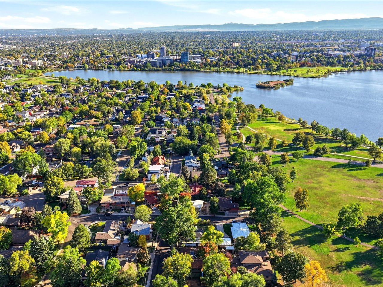 Tree-lined neighborhood beside a broad lake and green park, seen from above.