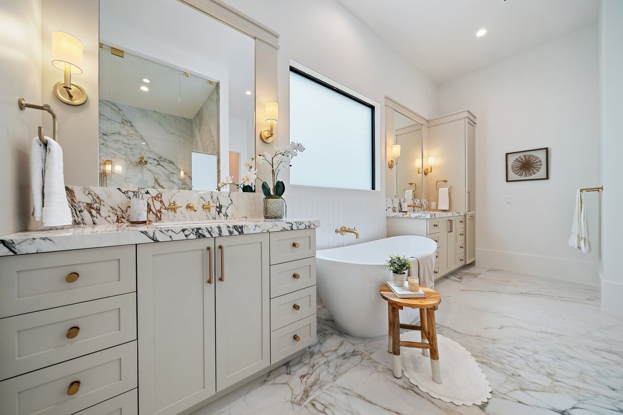 Luxury bathroom with a freestanding tub, veined marble, and brass fixtures.