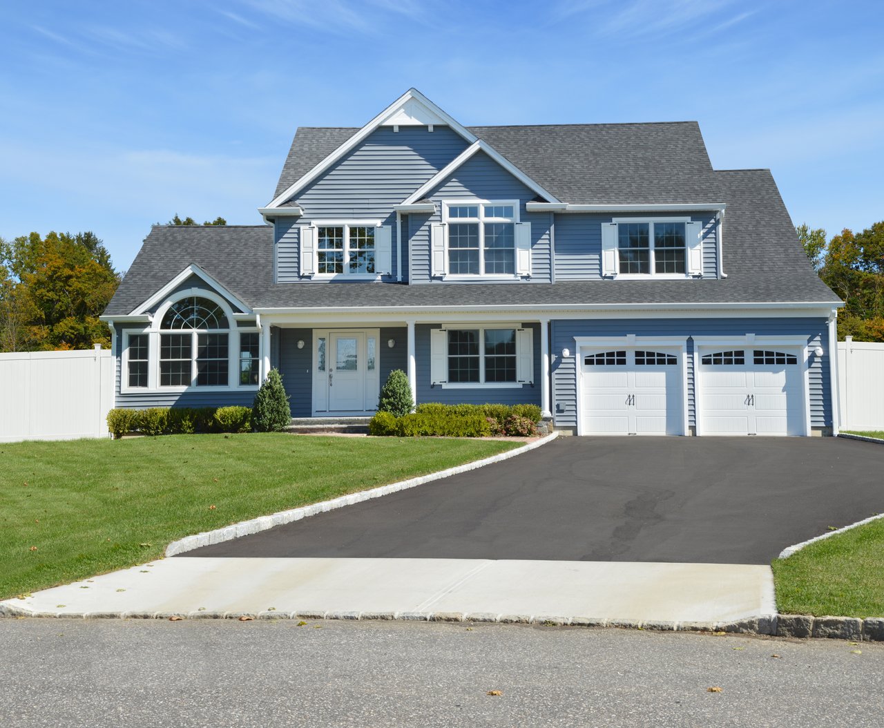 Blue two-story house with white trim, double garage, and broad driveway.