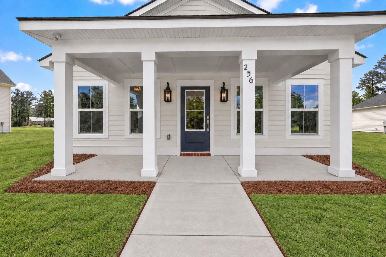 Home with a broad columned porch, dark blue front door, and walkway leading through the lawn.