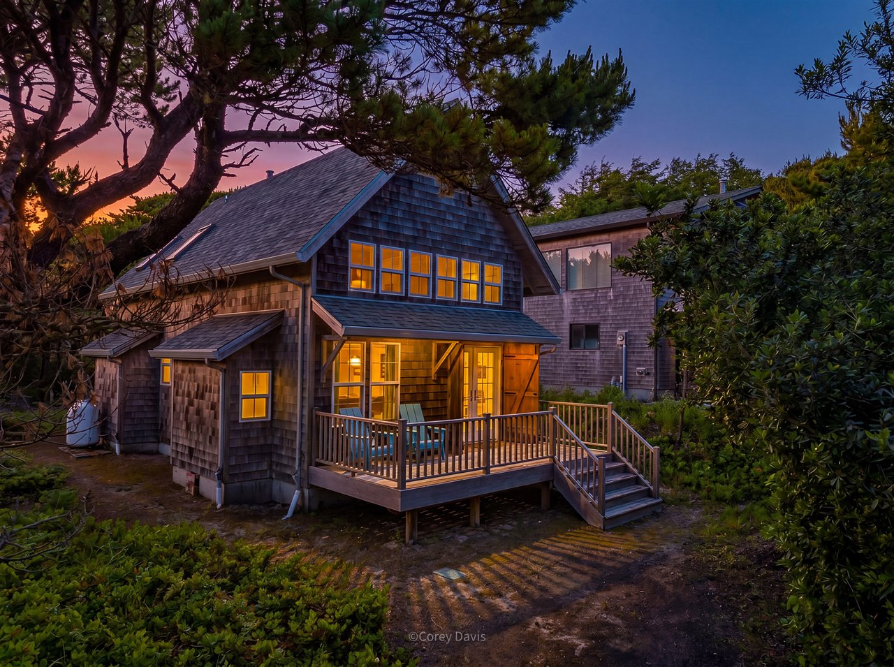 Sold beach cabin at 8864 Windward Ln in Manzanita, Oregon, represented by Shelley Parker of Home + Sea Realty, with wood interiors, a private loft, and beach access nearby.