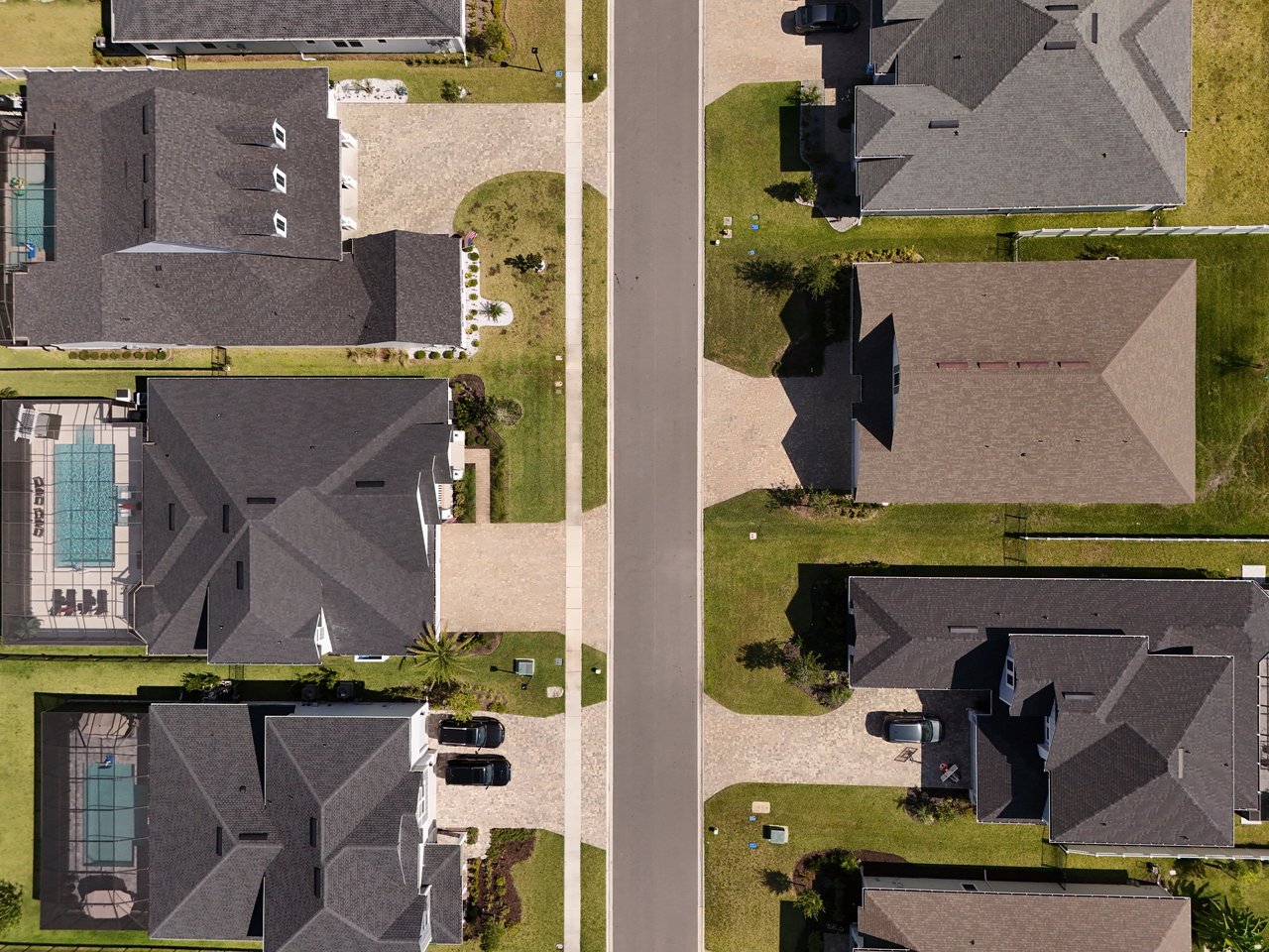 Aerial view of homes along a residential street, with screened pools and driveways.
