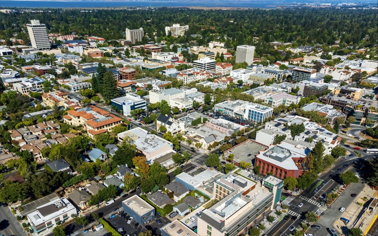 Aerial view of downtown Palo Alto, with leafy neighborhoods and the bay in the distance.