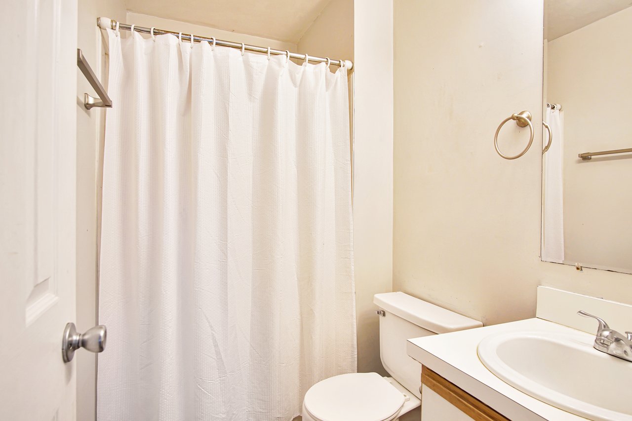 A clean bathroom featuring a toilet, sink, and a decorative shower curtain.