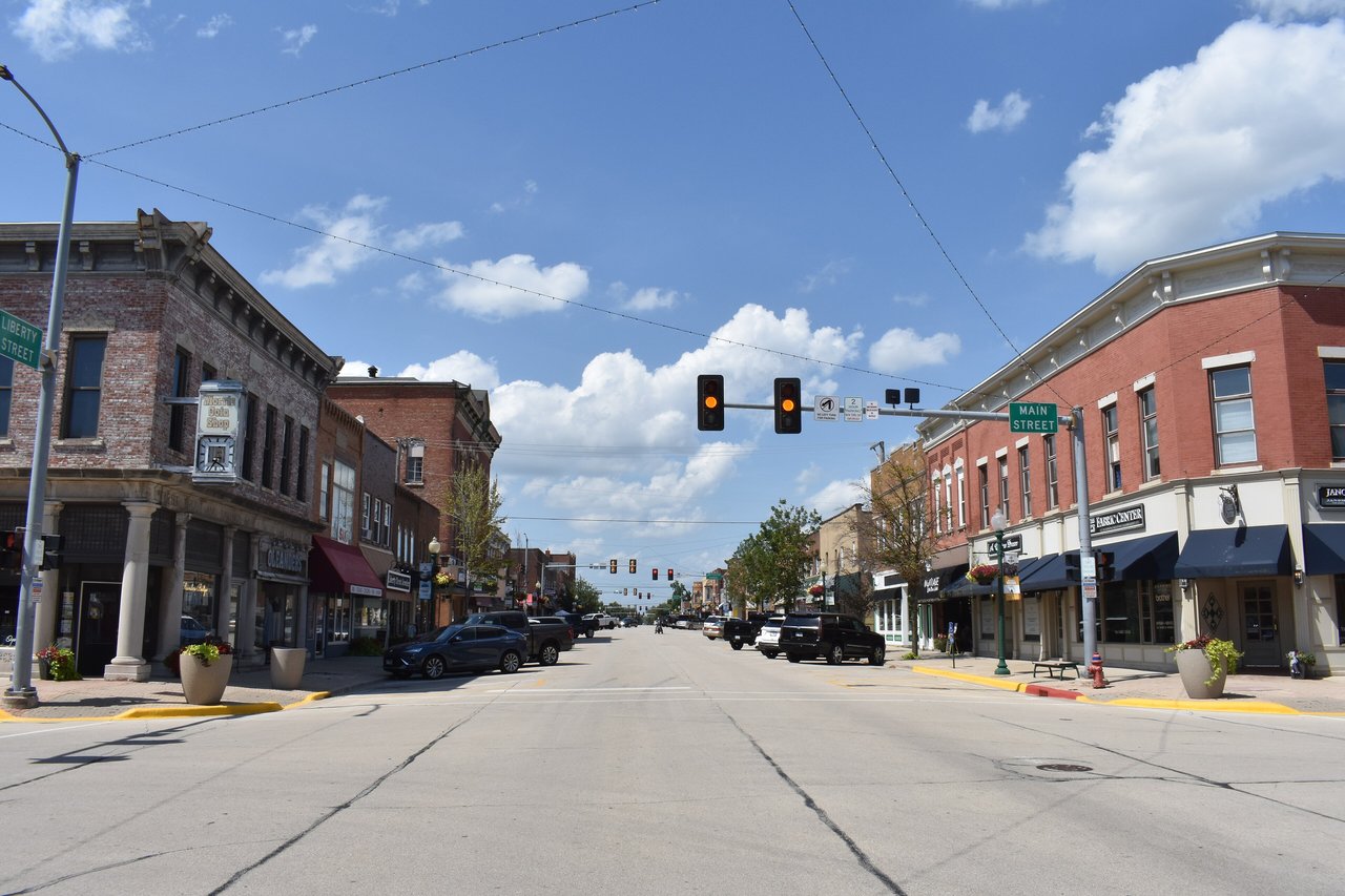 Liberty Street in downtown Morris, Illinois, lined with brick storefronts under a blue sky with clouds