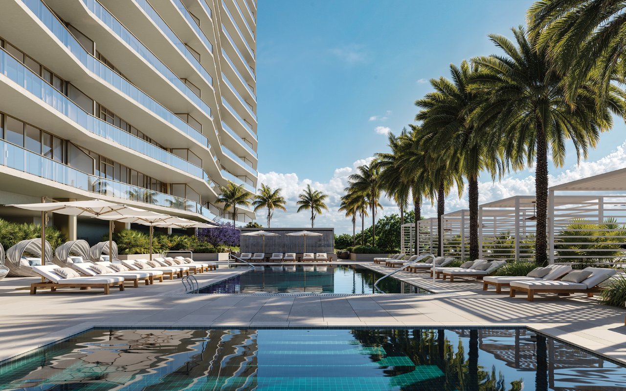 Condominium pool deck with lounge chairs, palm trees, and glass balconies.