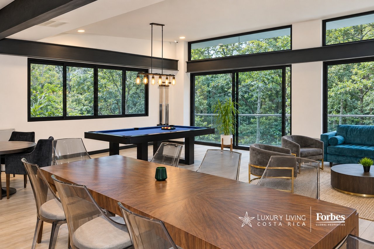 Furnished amenity room with a pool table, long dining table, and large windows overlooking greenery.