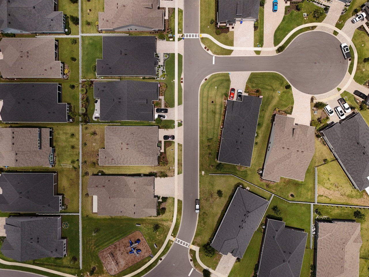 Aerial view of detached homes around a curved cul-de-sac and neighborhood playground.