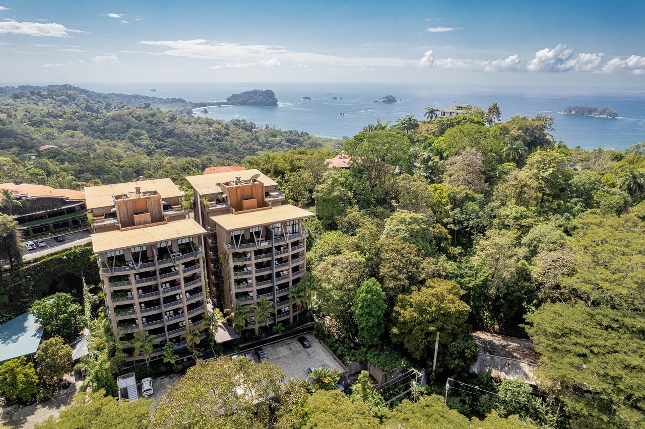 Condominium buildings amid tropical forest overlook the Pacific Ocean and offshore islands.