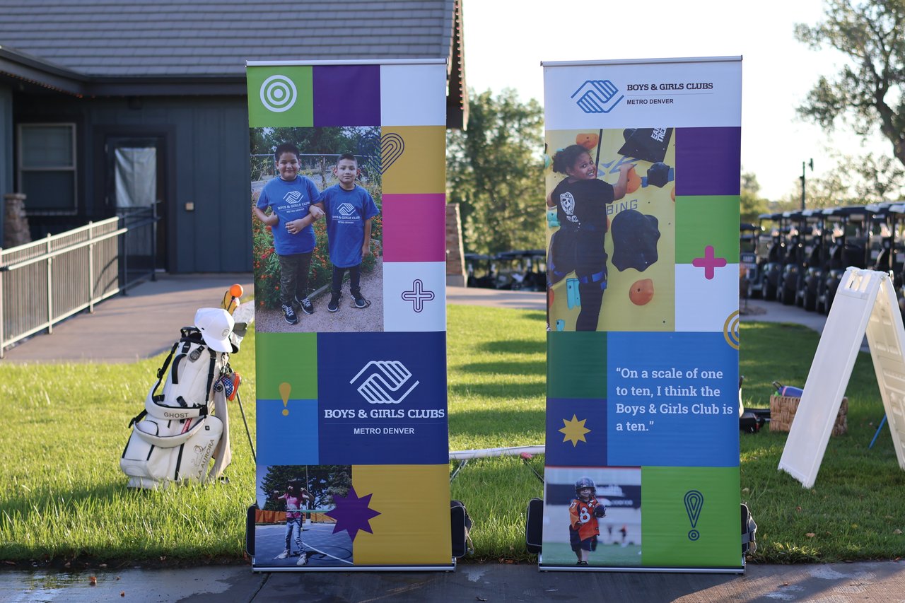 Boys & Girls Clubs Metro Denver banners display photos of children and a quote beside a golf course.