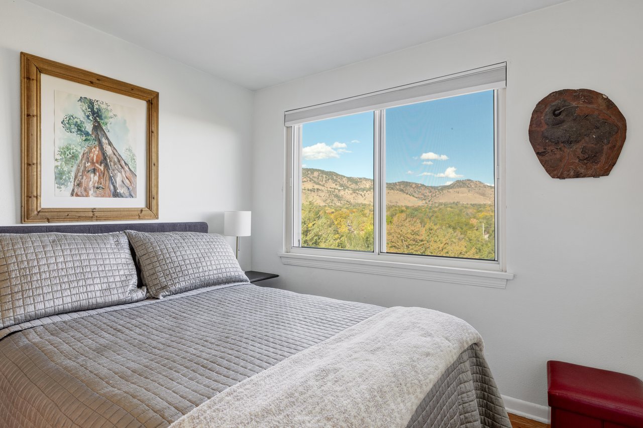 Second bedroom at 2003 Balsam Drive with a gray quilted bed and a window framing foothill views
