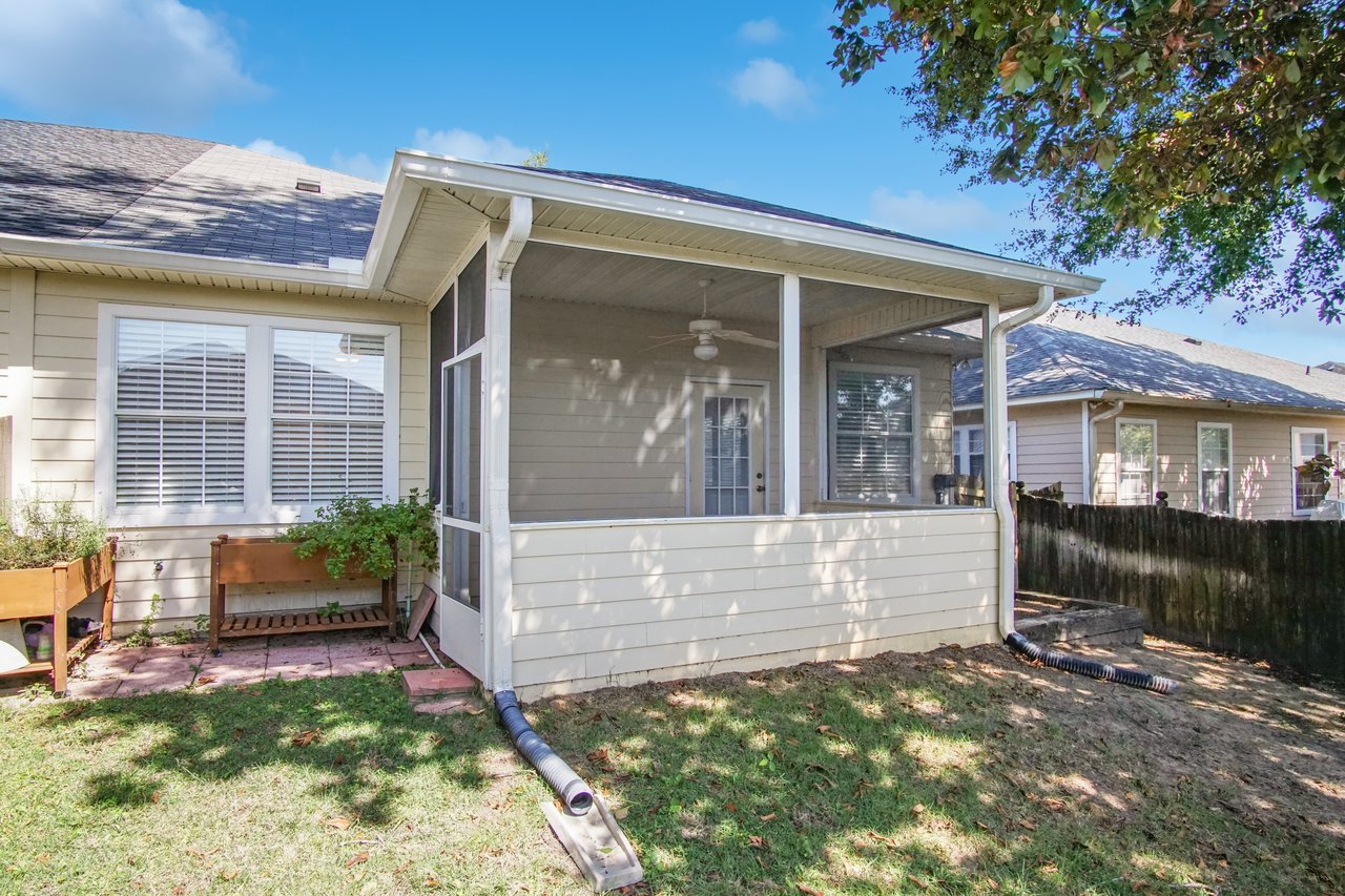 Rear exterior of 5441 Hampton Hill Circle, Tallahassee, Florida 32311 showing screened porch, windows with blinds, and fenced backyard.
