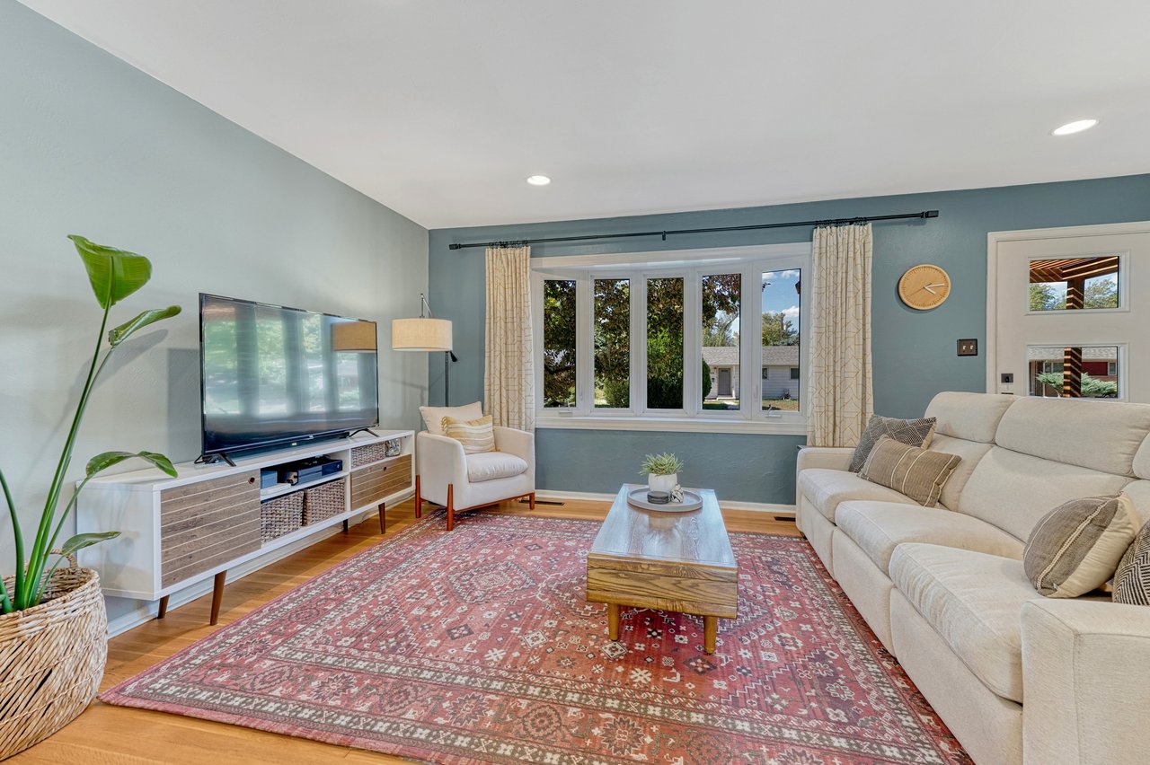 Living room with hardwood floors, a wall of front windows and recessed lighting