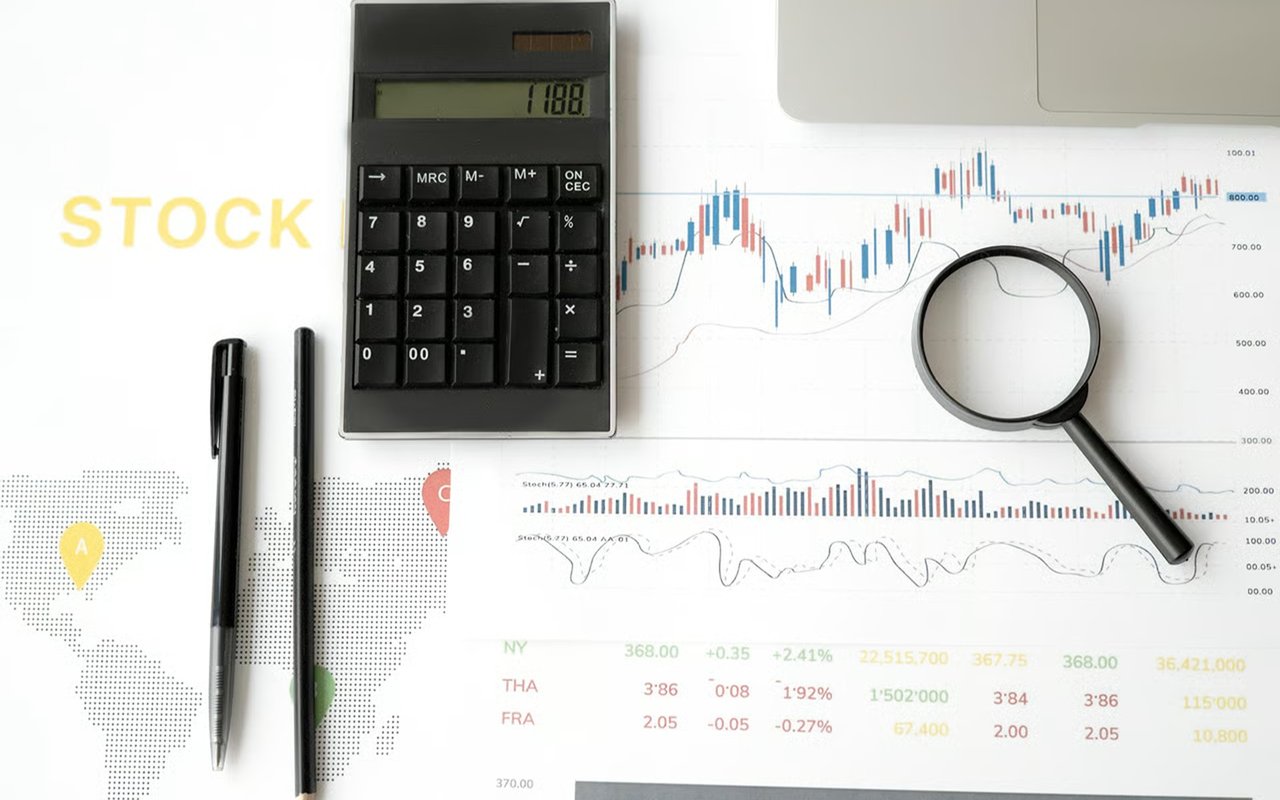 Calculator and magnifying glass on printed stock charts