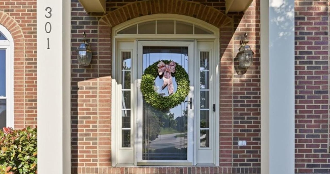 Brick home entrance with a glass front door, wreath, sidelights, lanterns, and the number 301.
