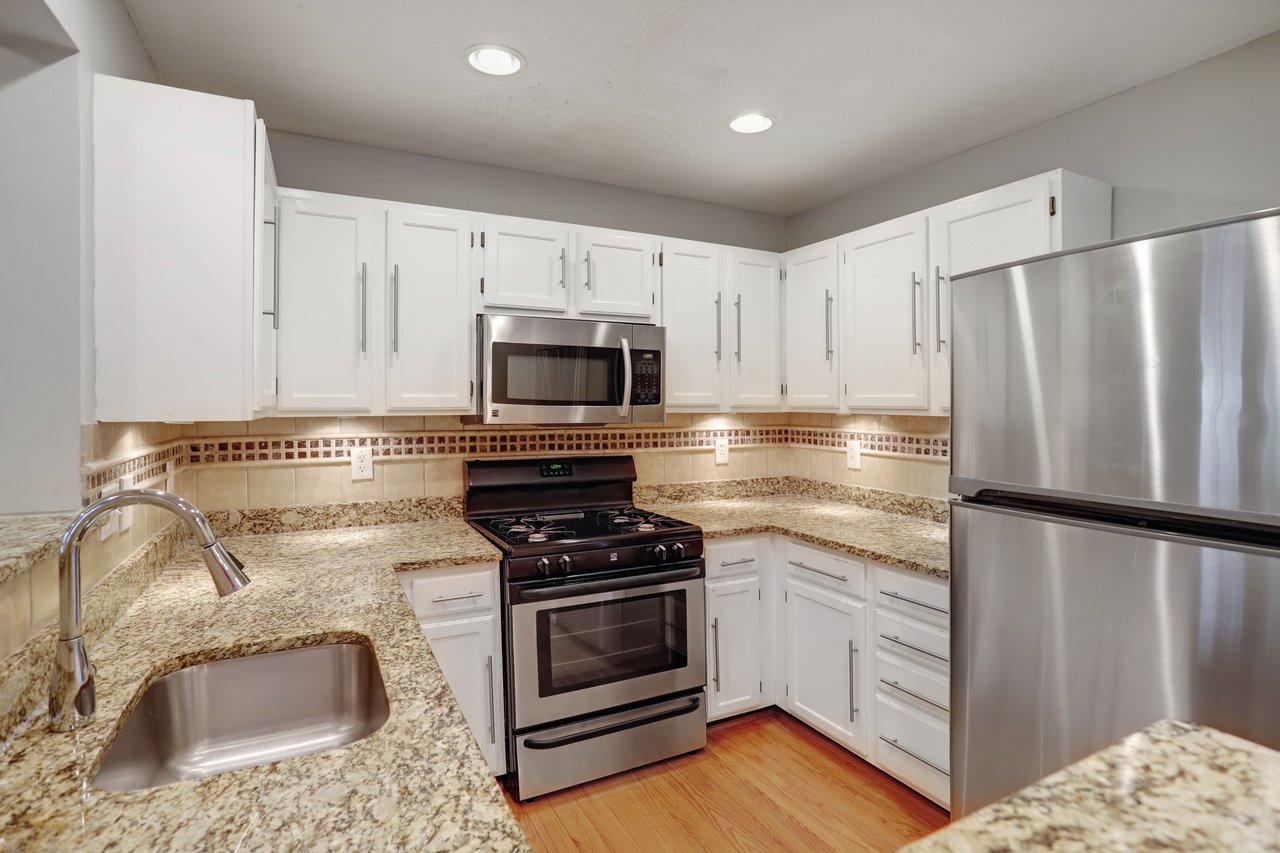 Kitchen with white cabinets, granite counters, stainless steel appliances, and a gas range.