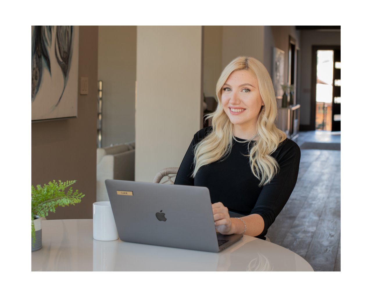 Megan Carr seated at a table with a laptop in a modern office.