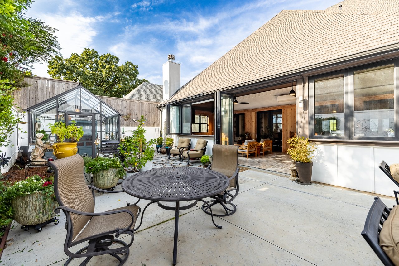 Backyard patio with a round metal table, planters, and open folding doors to the house.