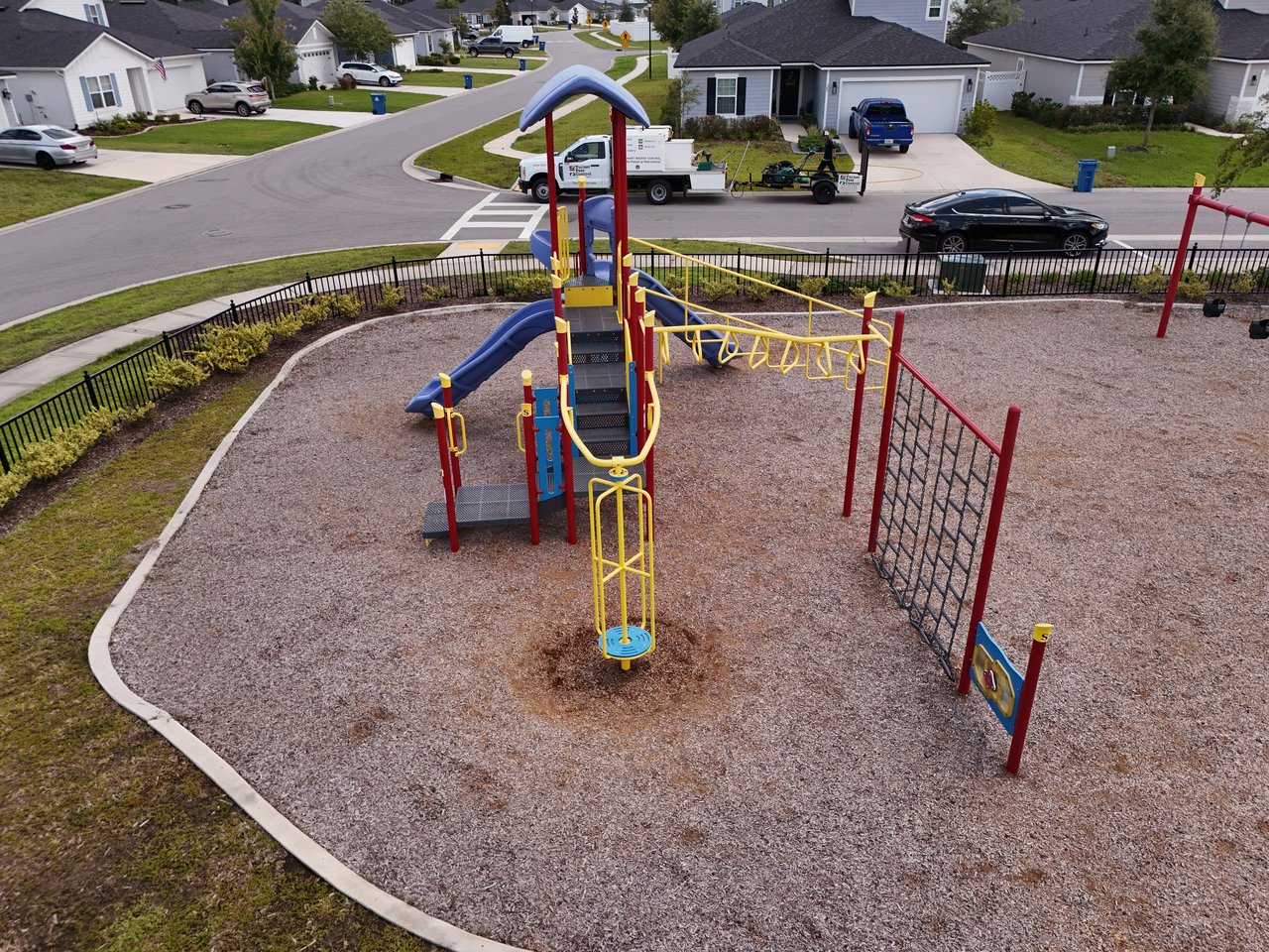 Neighborhood playground with colorful climbing equipment beside a residential street.