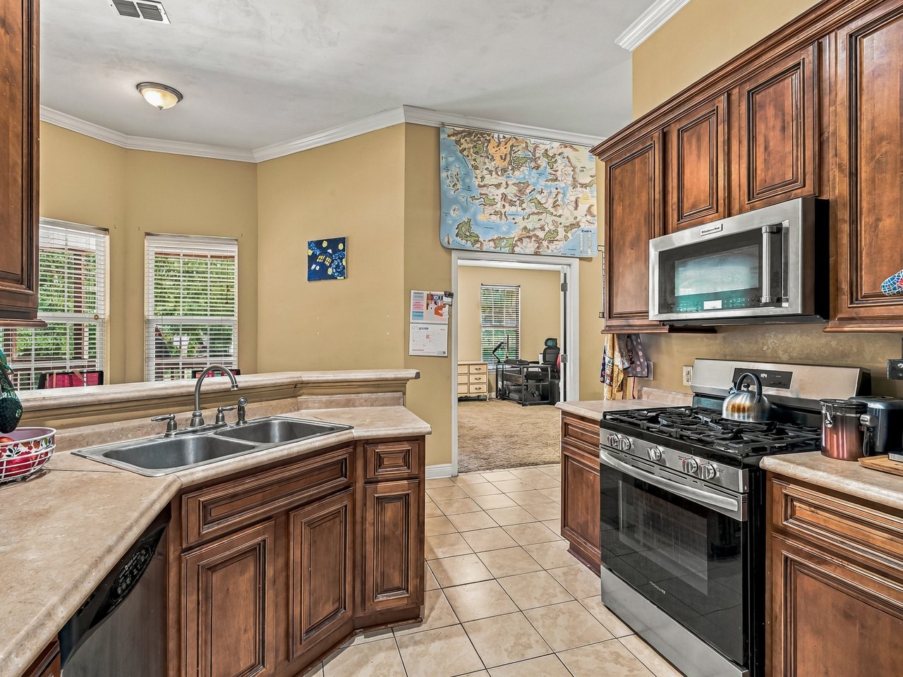 Kitchen with dark wood cabinetry, stone counters, a double sink, and stainless steel appliances.