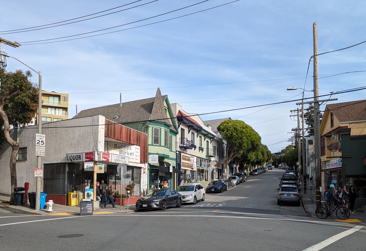 Street-level view of Glen Park in San Francisco, showing local shops, pedestrians, parked cars, and classic architecture along a quiet neighborhood street