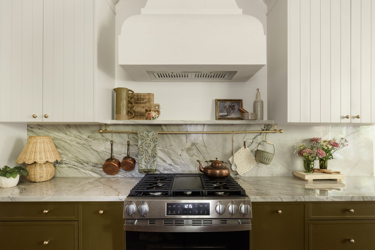Furnished kitchen with a stainless-steel range, marble backsplash, white cabinets, and olive-green lower cabinets.