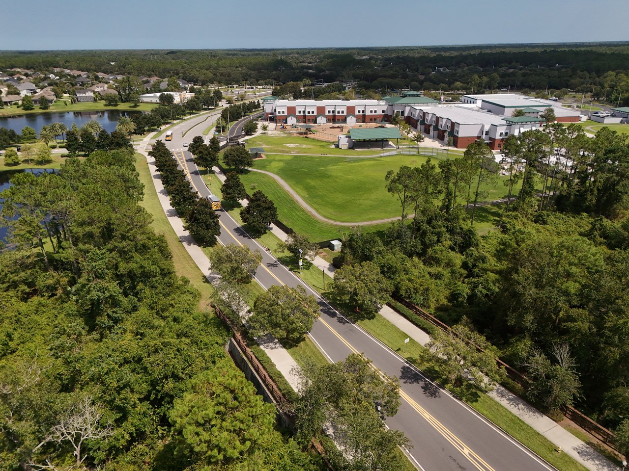 Aerial view of a tree-lined Nocatee neighborhood road, ponds, homes, and a large campus.
