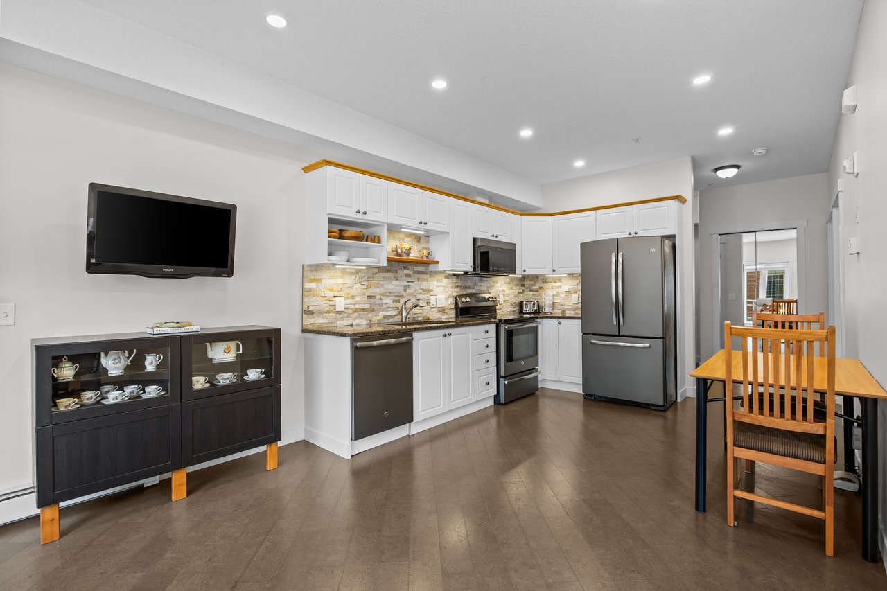Kitchen with white cabinets, stainless steel appliances, and a wooden dining table.