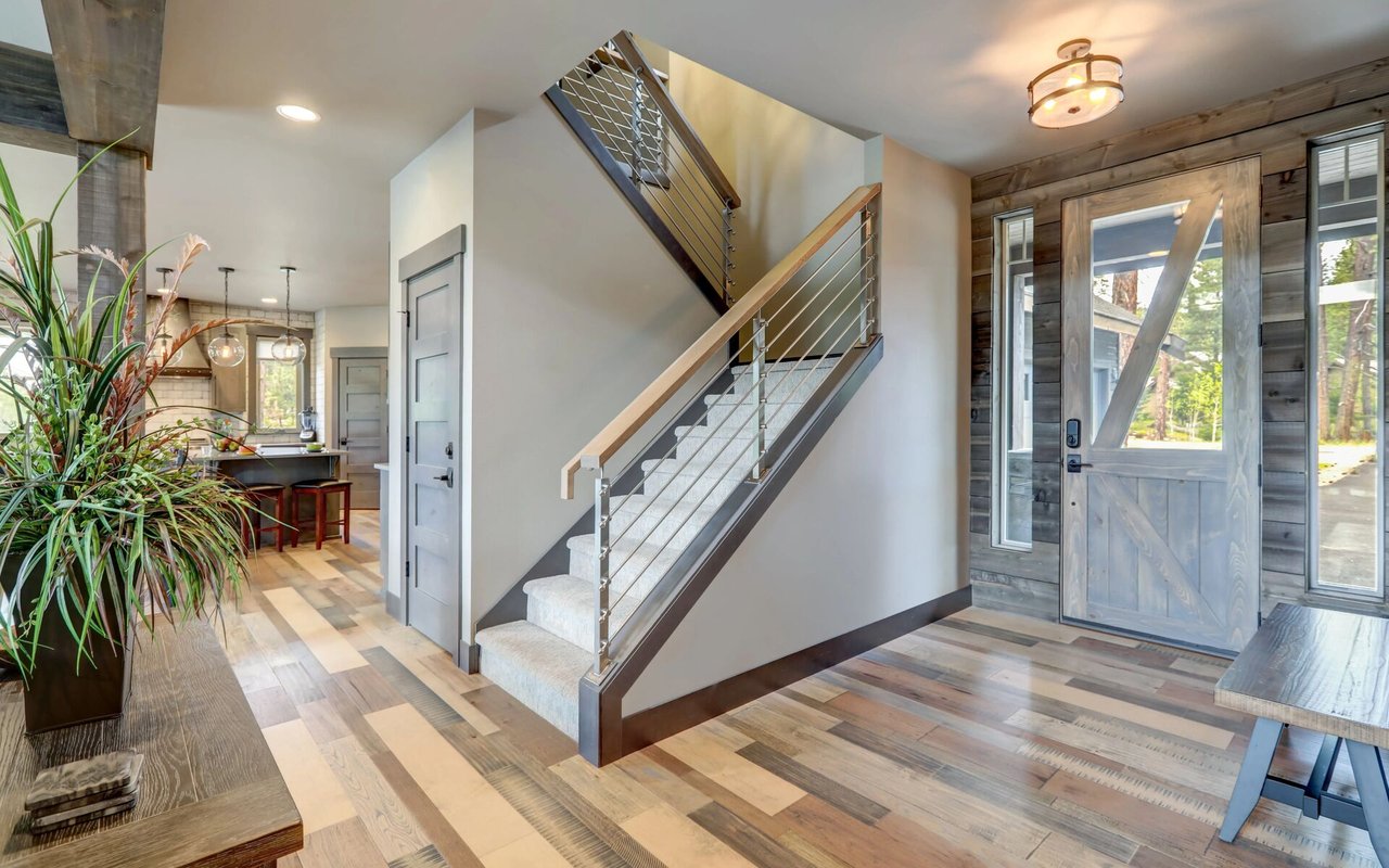 Home entryway with a carpeted staircase, metal railings, and a gray wood front door.