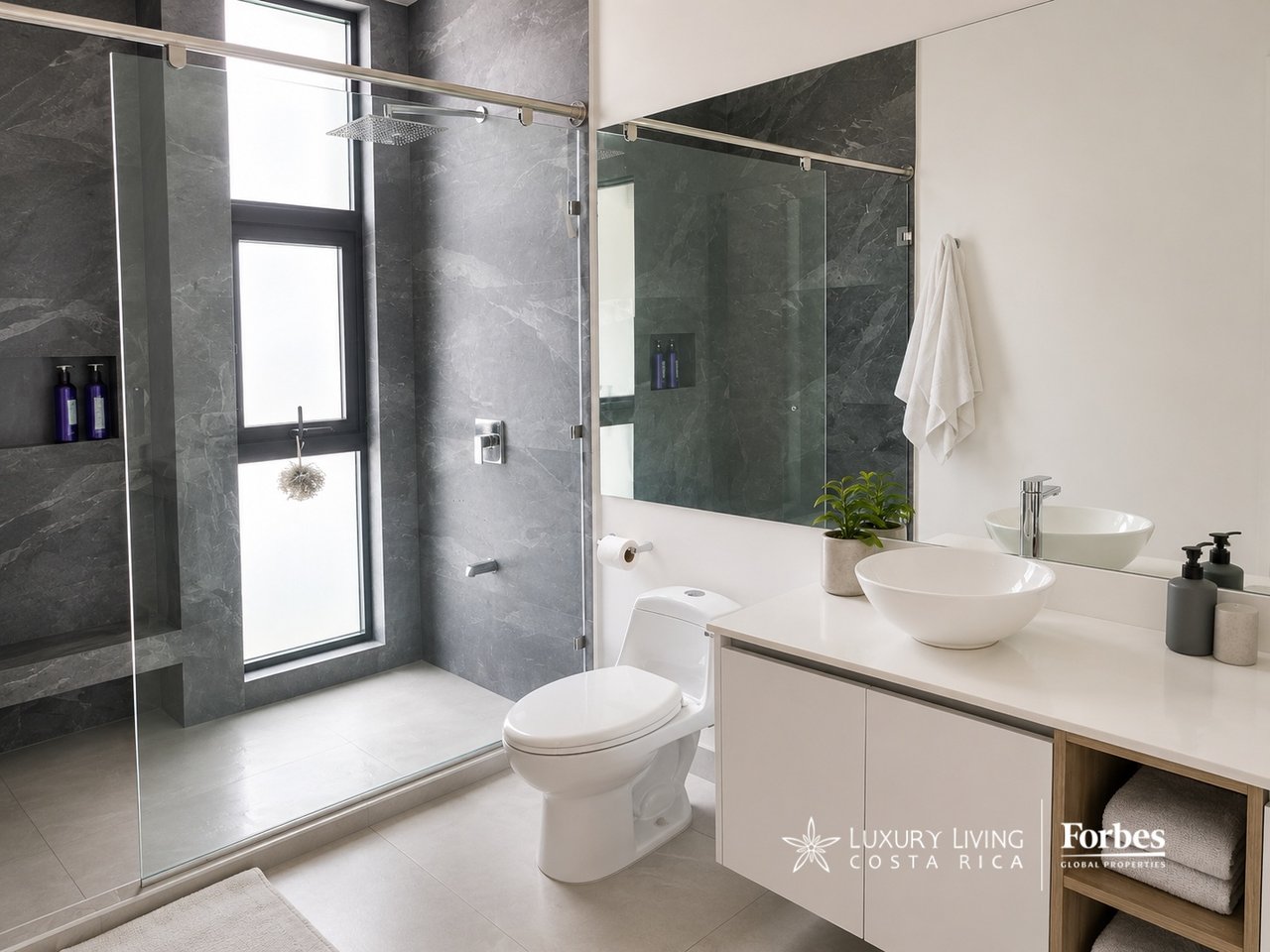 Modern bathroom with a glass-enclosed shower, dark stone tile, and white vessel sink.