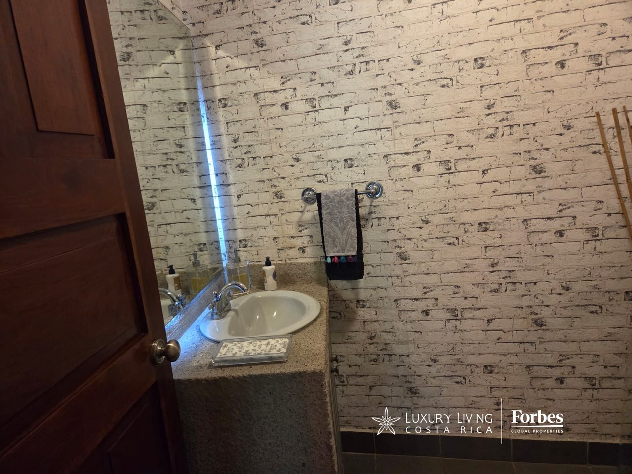 Bathroom vanity with an oval sink, speckled stone counter, and distressed white brick-pattern walls.