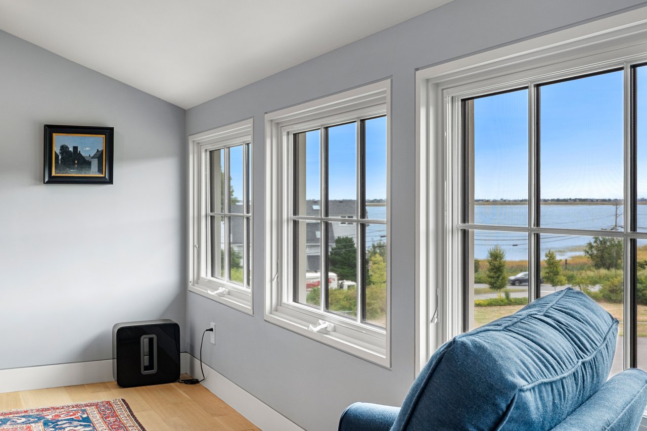 Sitting area with blue sofa and large windows overlooking the water.