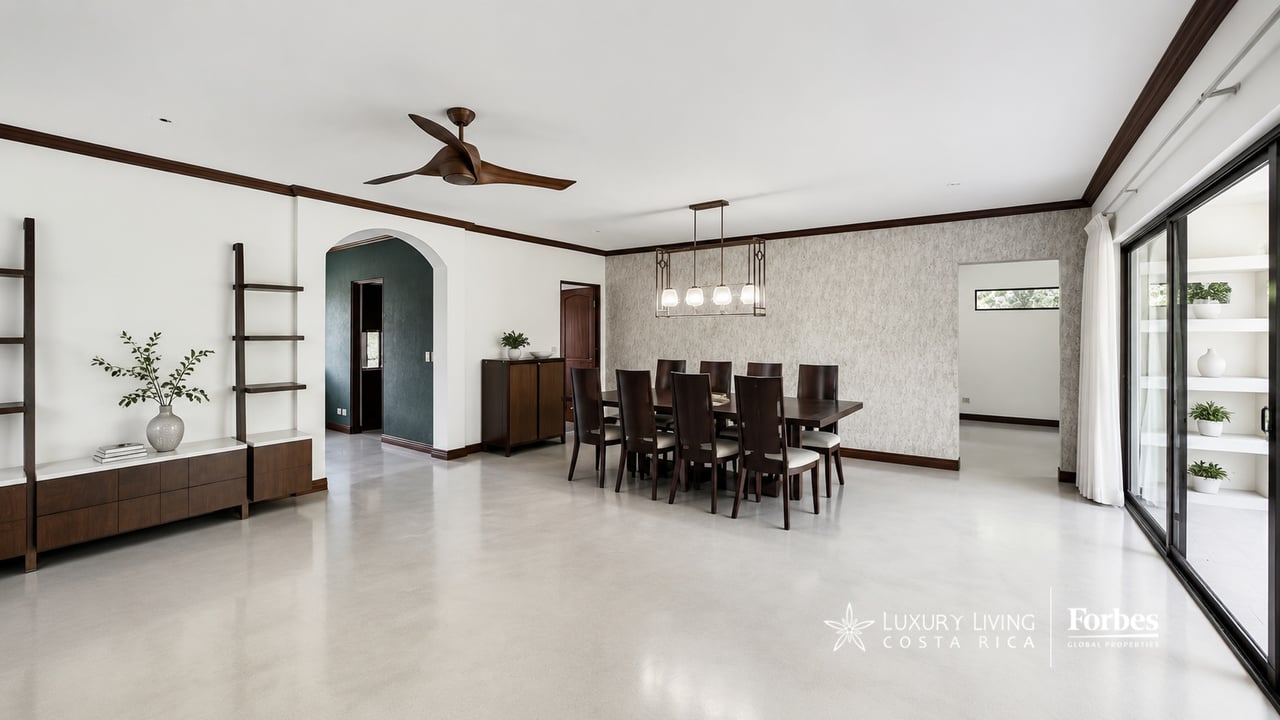 Dining room with a long dark wood table, ceiling fan, and sliding glass doors.