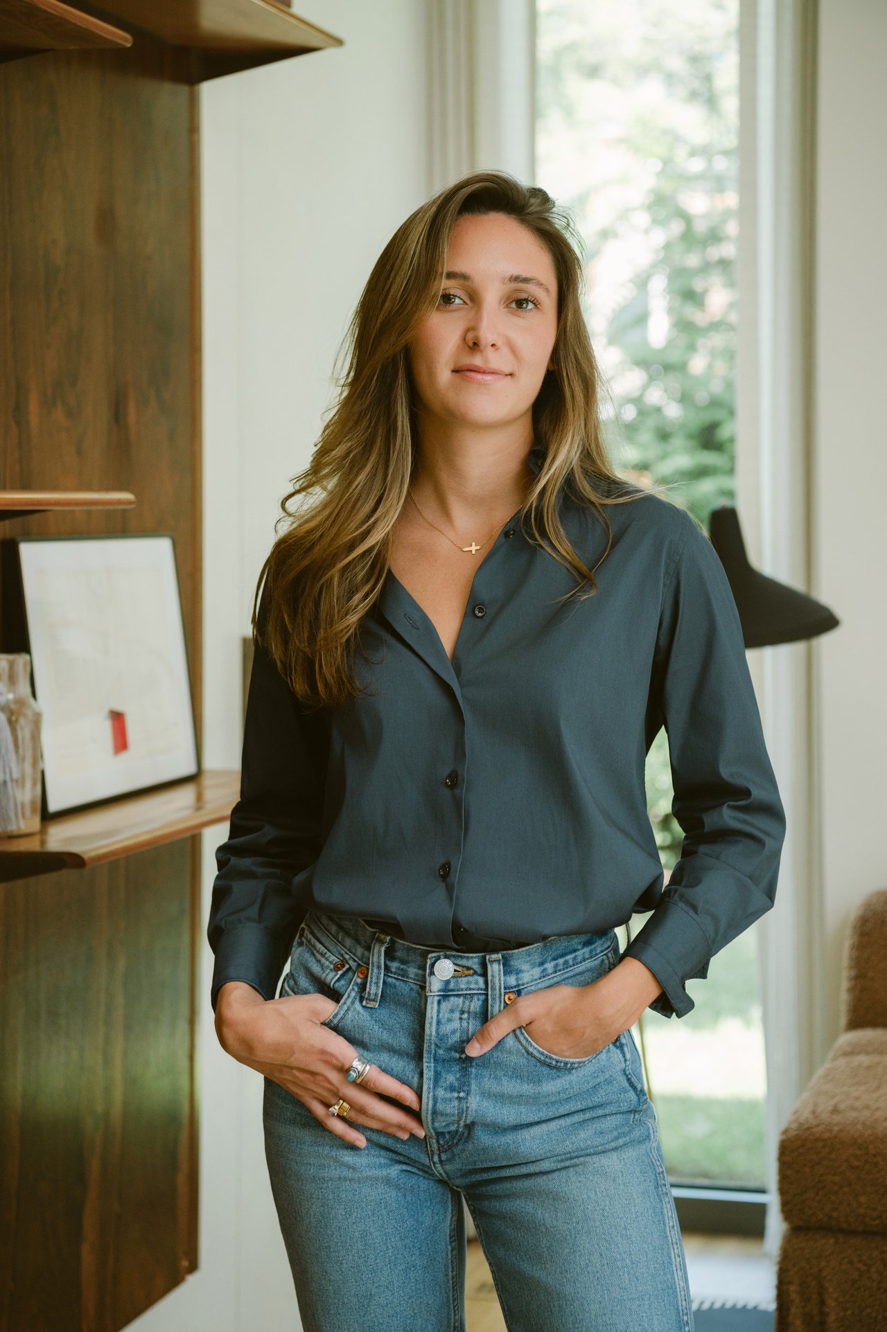 Elizabeth Bistrian in a dark blue shirt and jeans, standing in a bright office.
