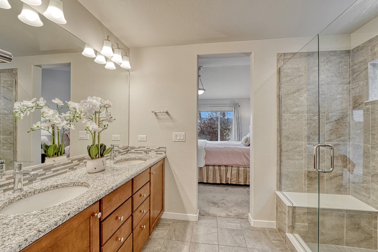 Primary bathroom with glass-enclosed tiled shower, bench seat and double vanity