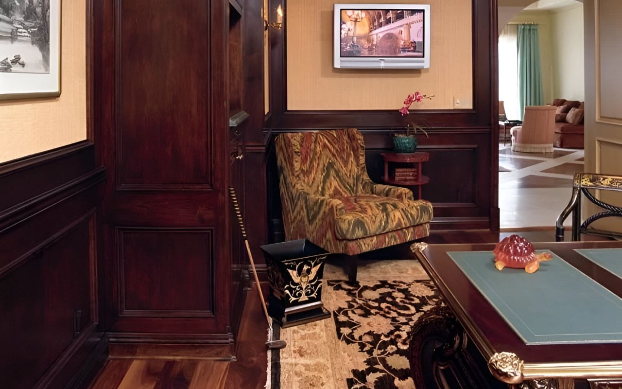 Gentleman’s game room with mahogany paneling, a patterned armchair, and a pool table.