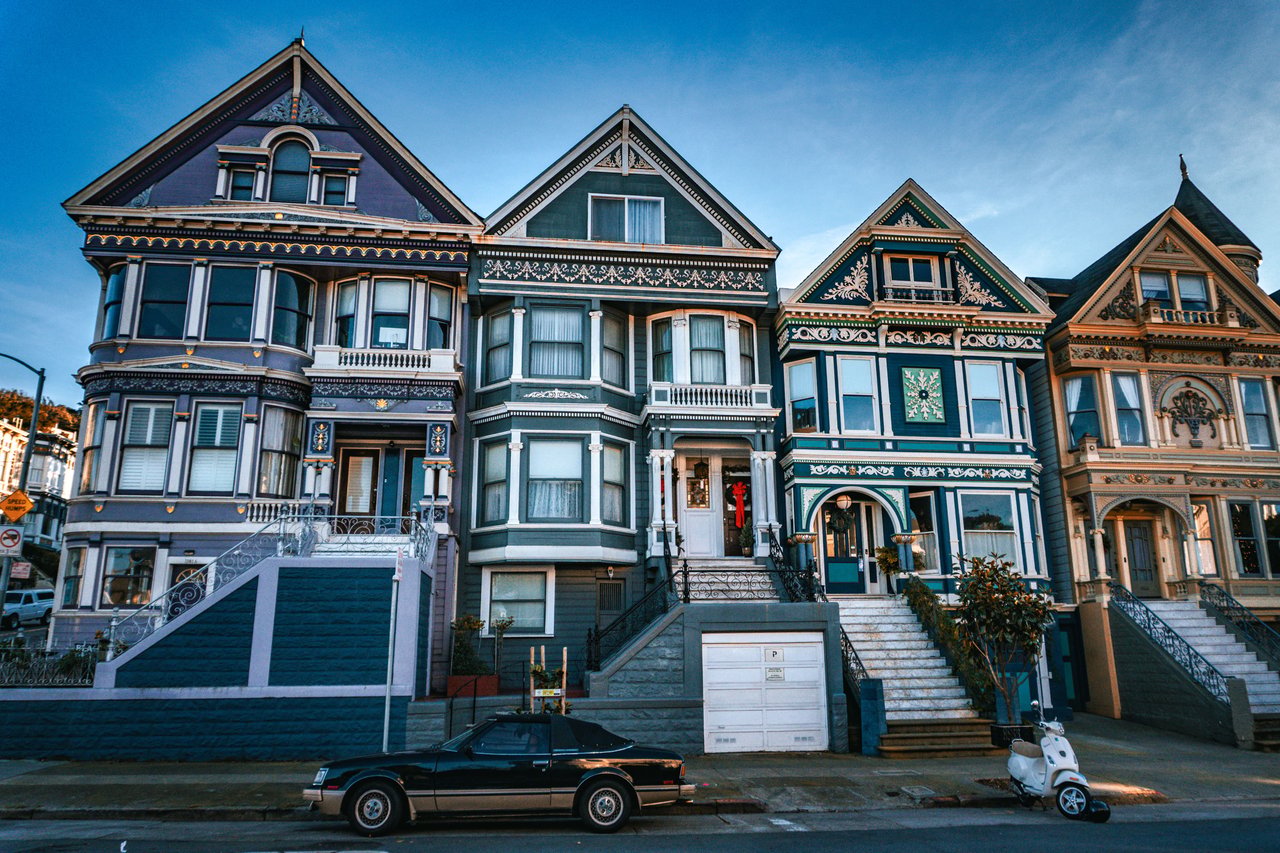 Colorful Victorian houses with ornate trim and steep gabled roofs on a San Francisco street.