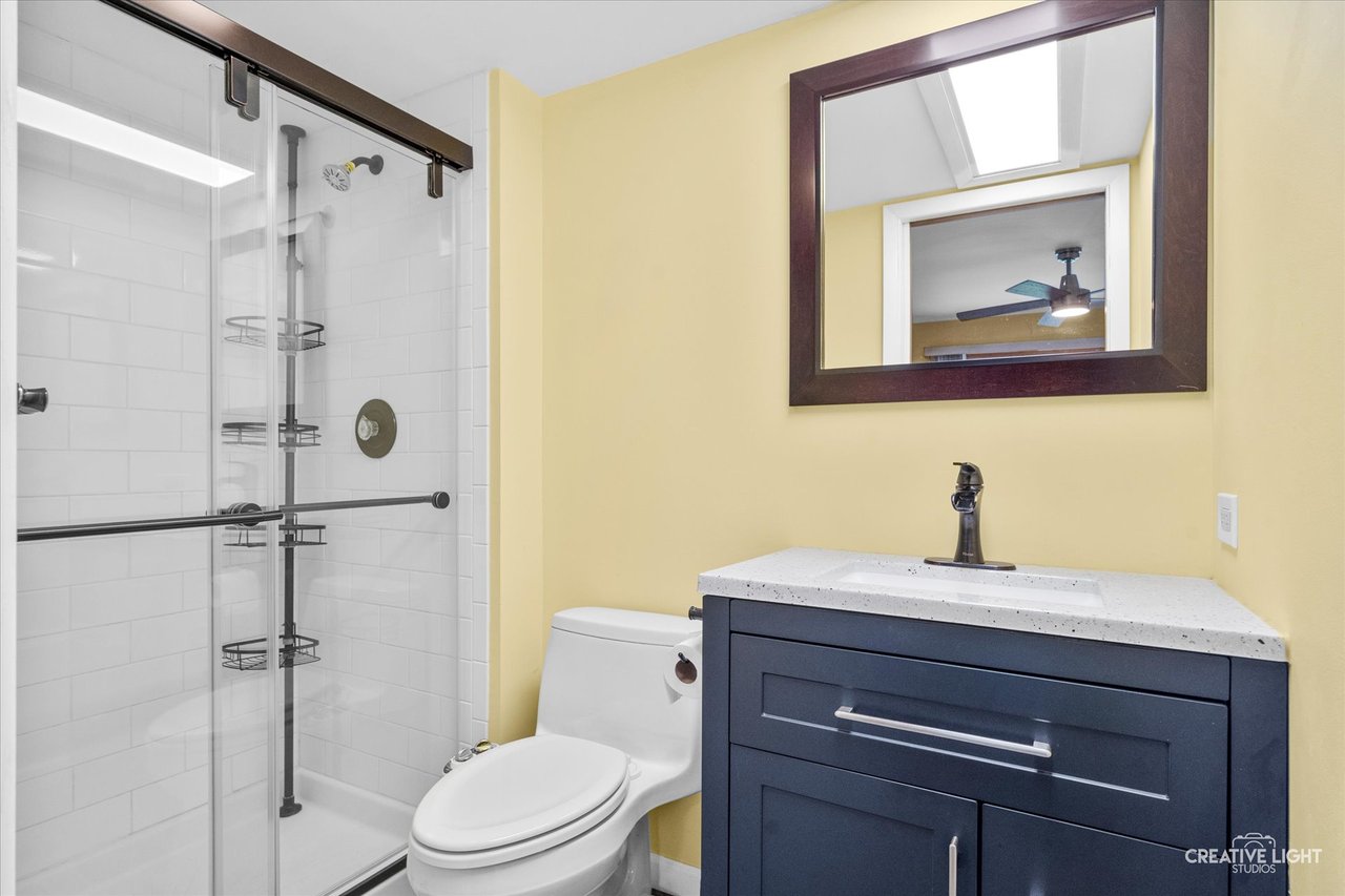 Remodeled primary bathroom with step in shower and rain shower head at 8316 Woodland Drive Darien IL