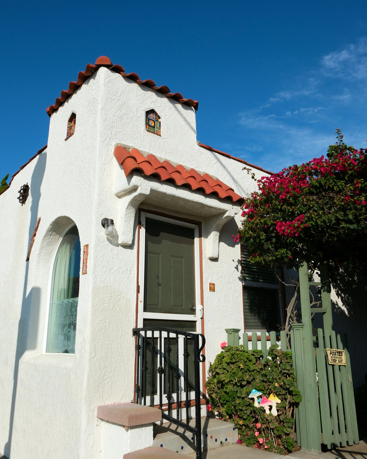 White stucco Spanish Mediterranean-style house with a red tile roof and flowering bougainvillea