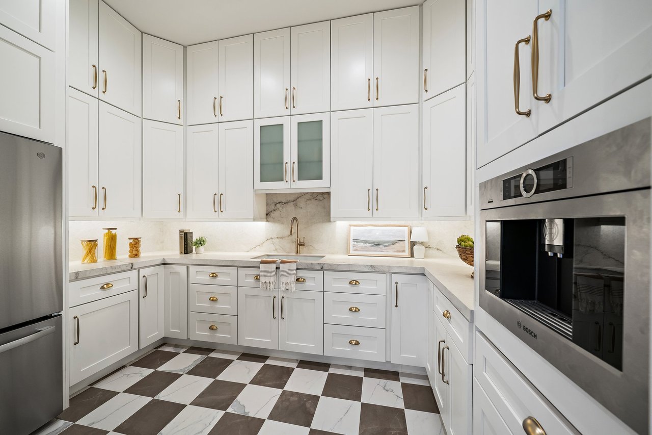 Kitchen with ceiling-height white cabinets, brass hardware, and a patterned brown-and-white tile floor.