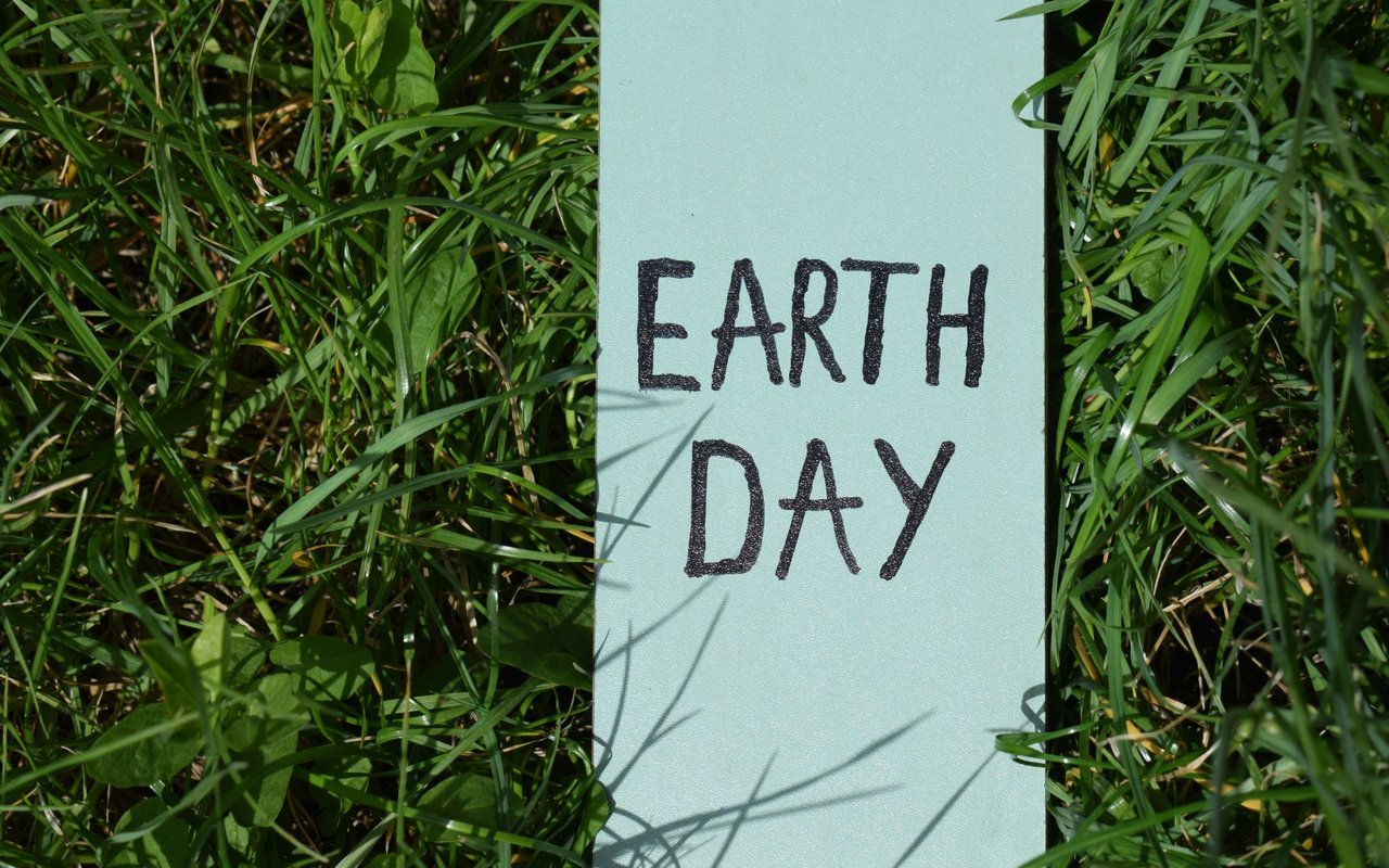 Earth Day sign surrounded by long green grass.