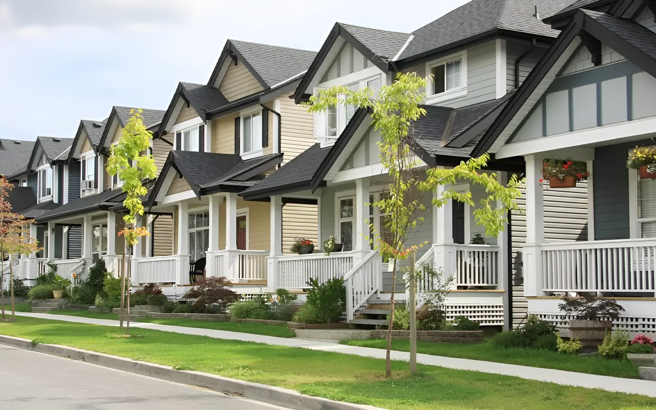 Row of townhouses with white-railed porches and landscaped front lawns.