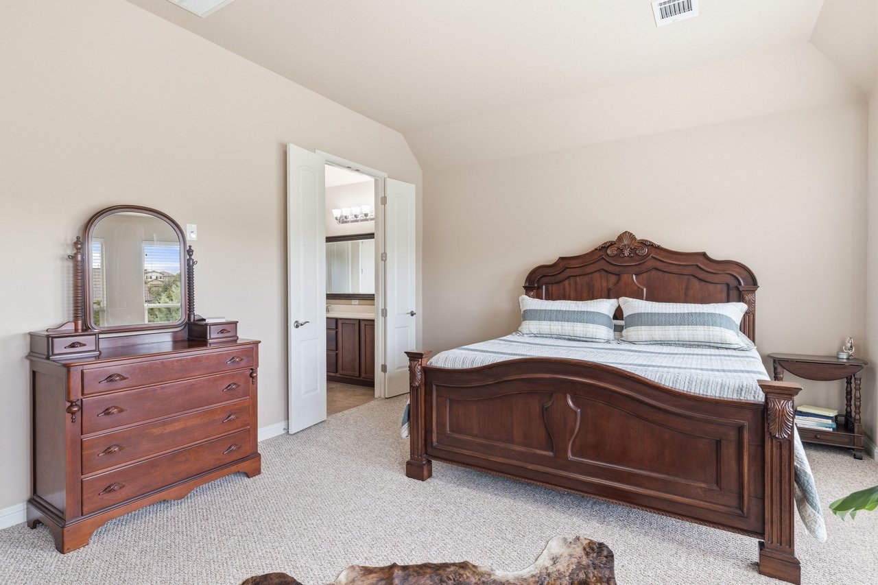 Bedroom with a carved dark wood bed and matching dresser, opening to an en-suite bathroom.
