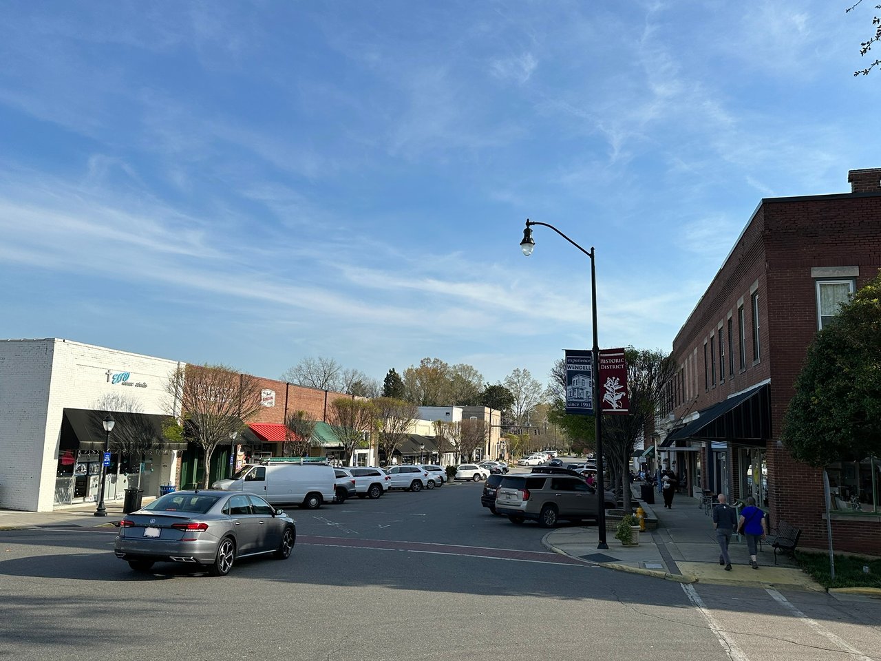 Downtown Wendell street with historic district banners, brick storefronts, and parked cars.