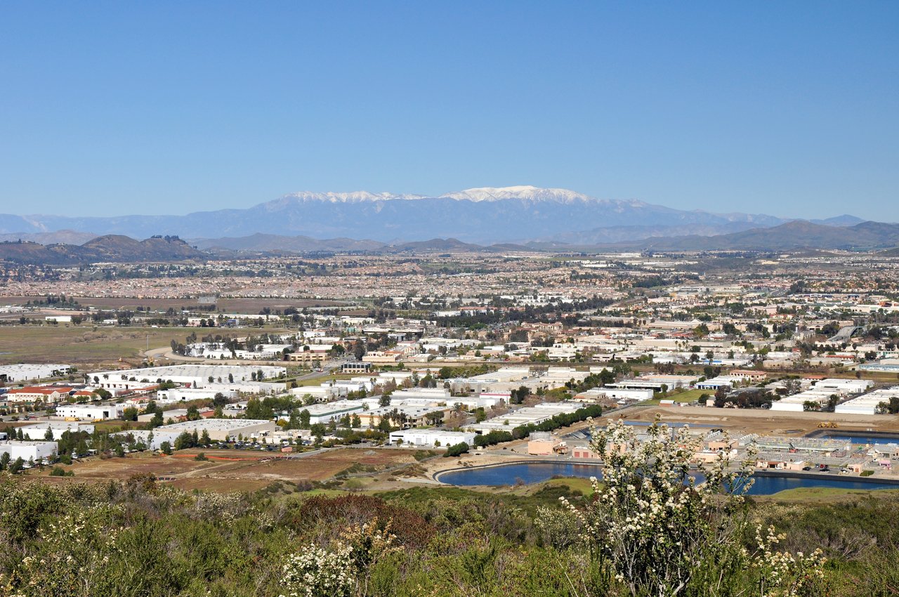 Valley city and reservoir below distant snow-capped mountains.