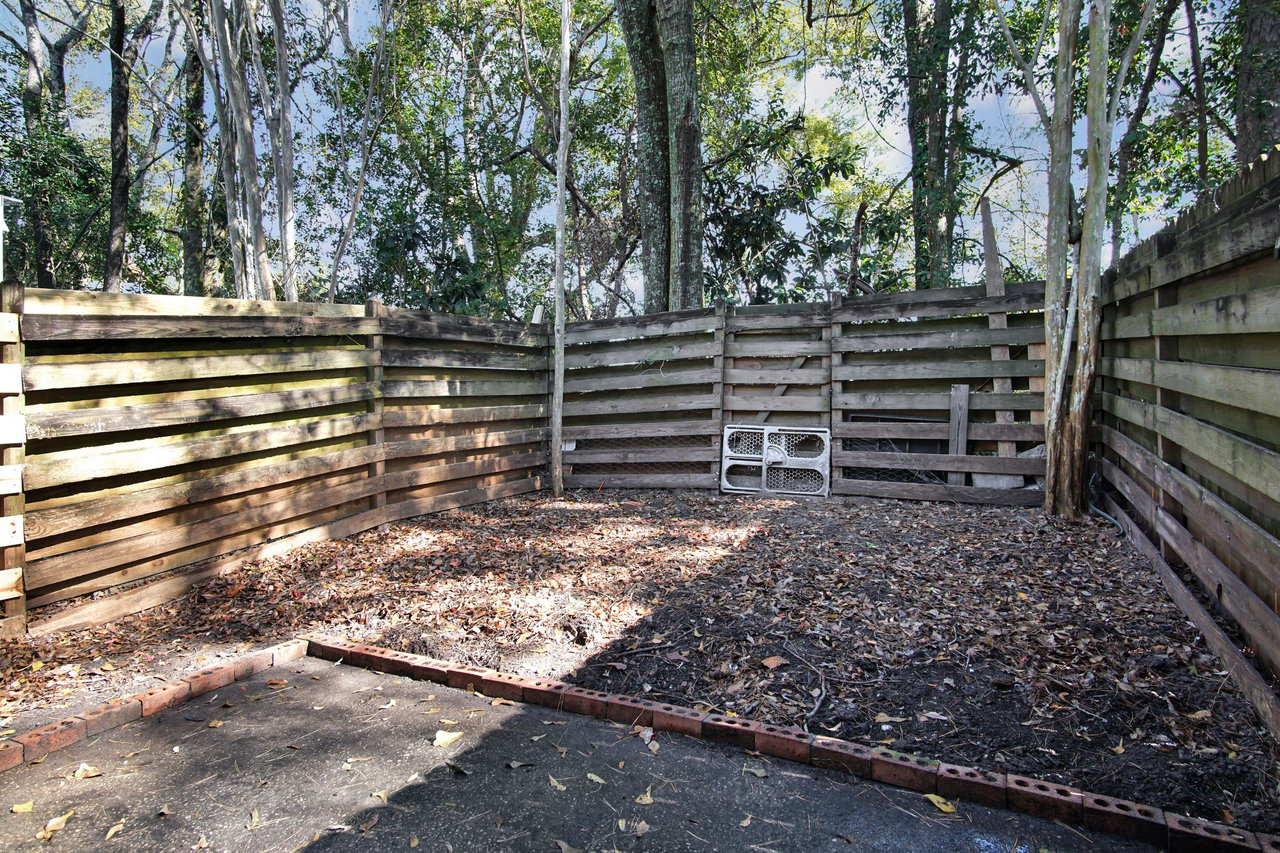 A small fenced area featuring a bench beside a tree, providing a tranquil outdoor space for relaxation.