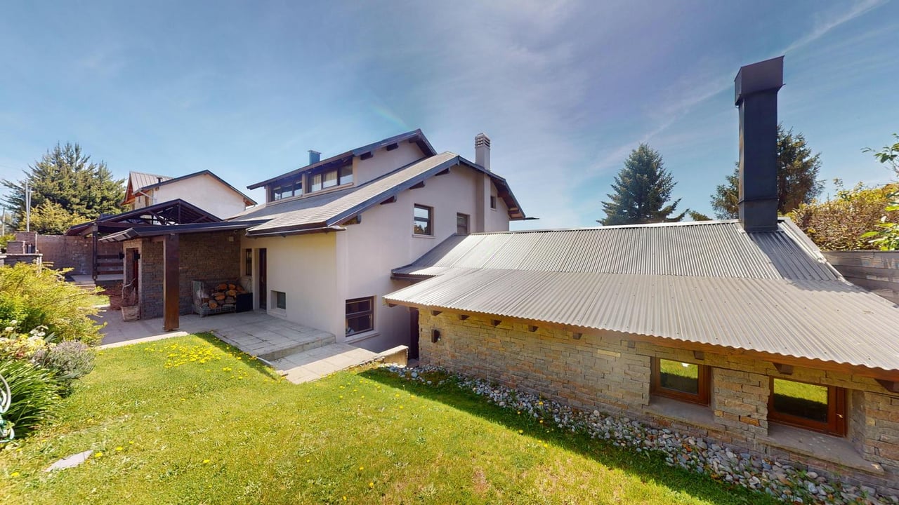 Casa with a stone outbuilding, covered patio, and sunny lawn.