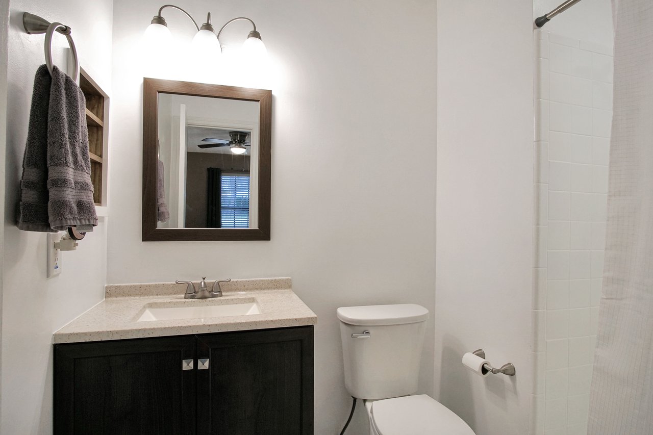 A clean bathroom featuring a toilet, sink, and mirror, showcasing a modern and functional design.